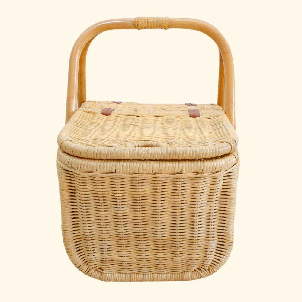 Side view of Aurelie rattan picnic basket by MOMIJI with a lid and handle on a beige background.