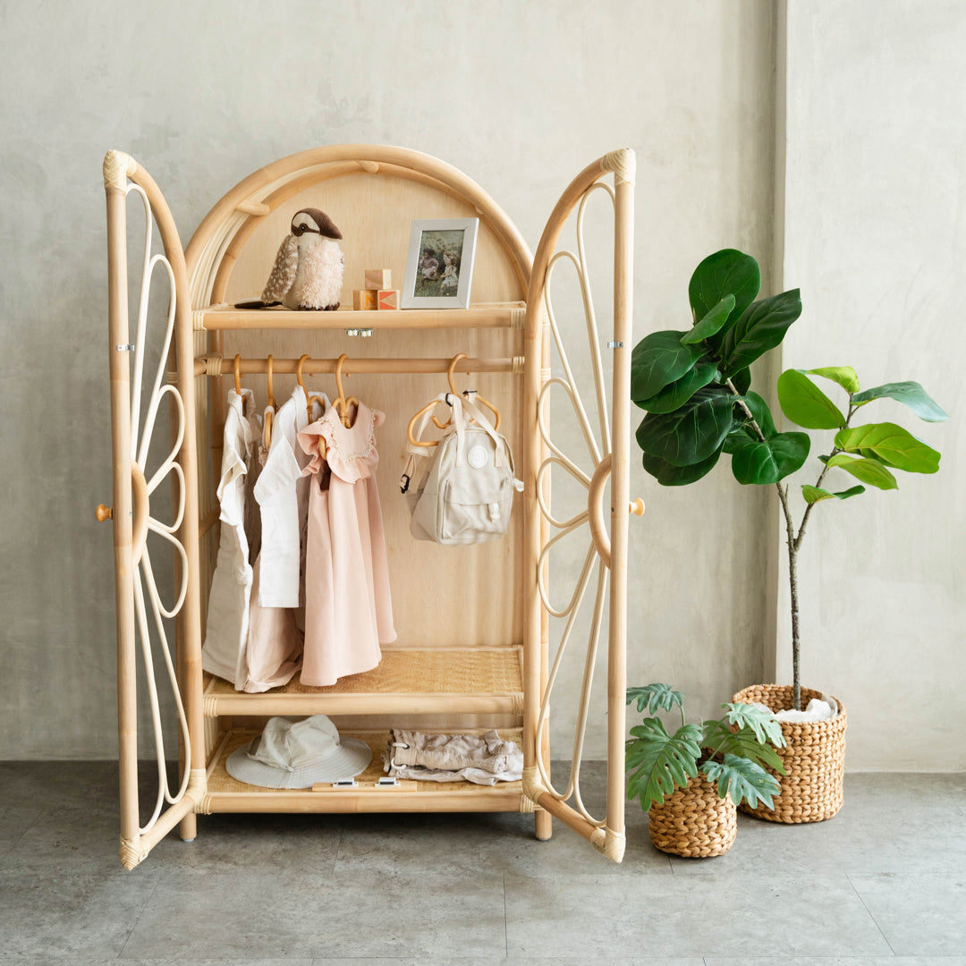 Wooden rattan wardrobe with clothes and accessories, plants in the background
