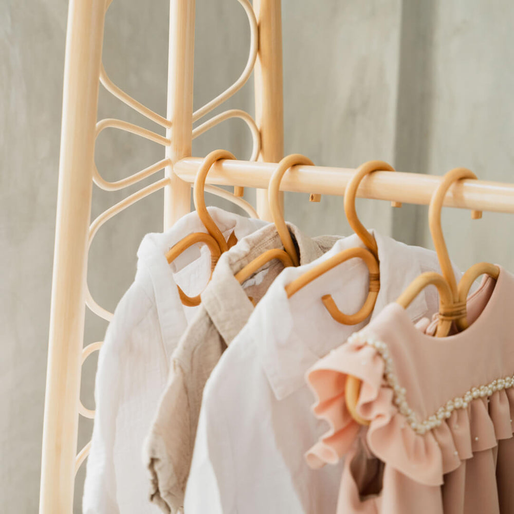 Clothes hung using Rattan Clothes Hangers on the Belle Children's Clothes Rack with 2 Drawers by MOMIJI with detail carving of rack in background