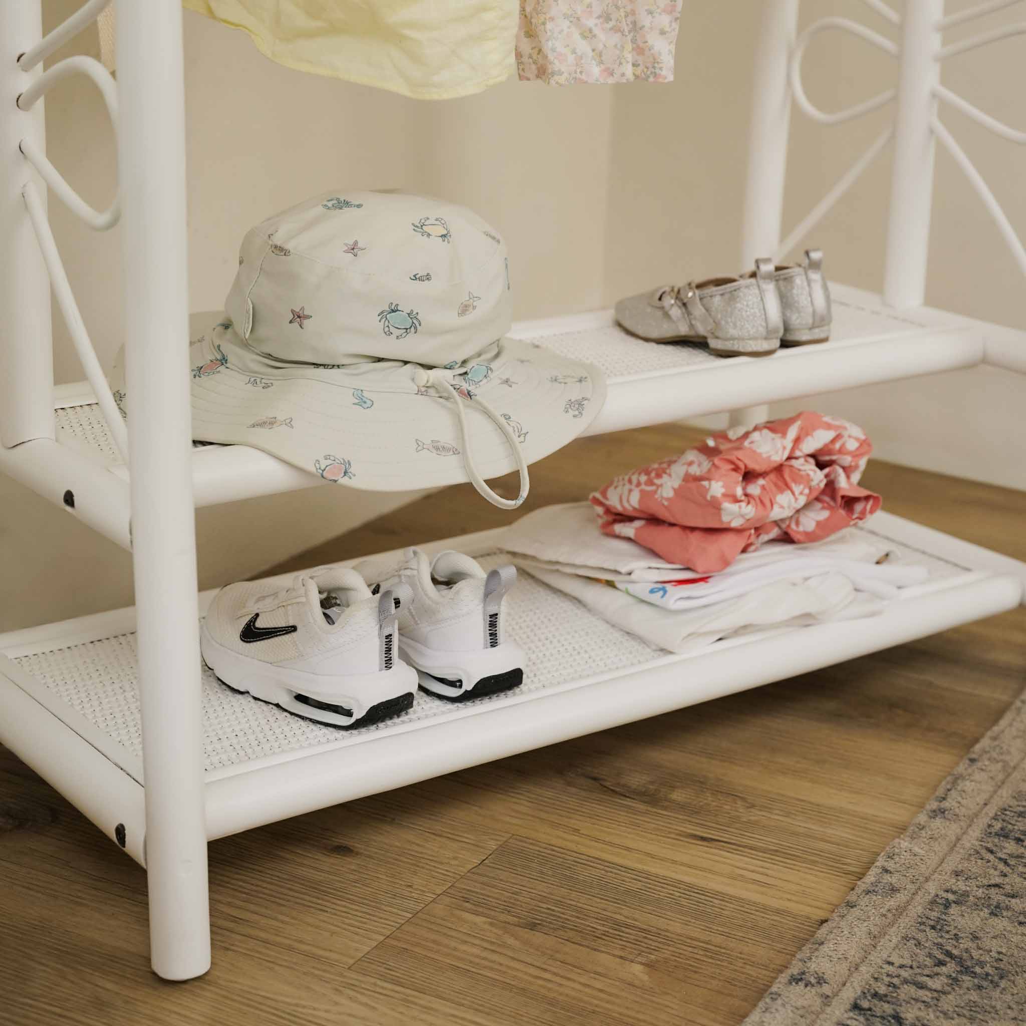 Close-up of the two-tier shelves of the handcrafted white rattan Belle Kids Montessori Clothing Rack by MOMIJI, showcasing multifunctional storage for shoes, accessories, hats, and everyday children's essentials.