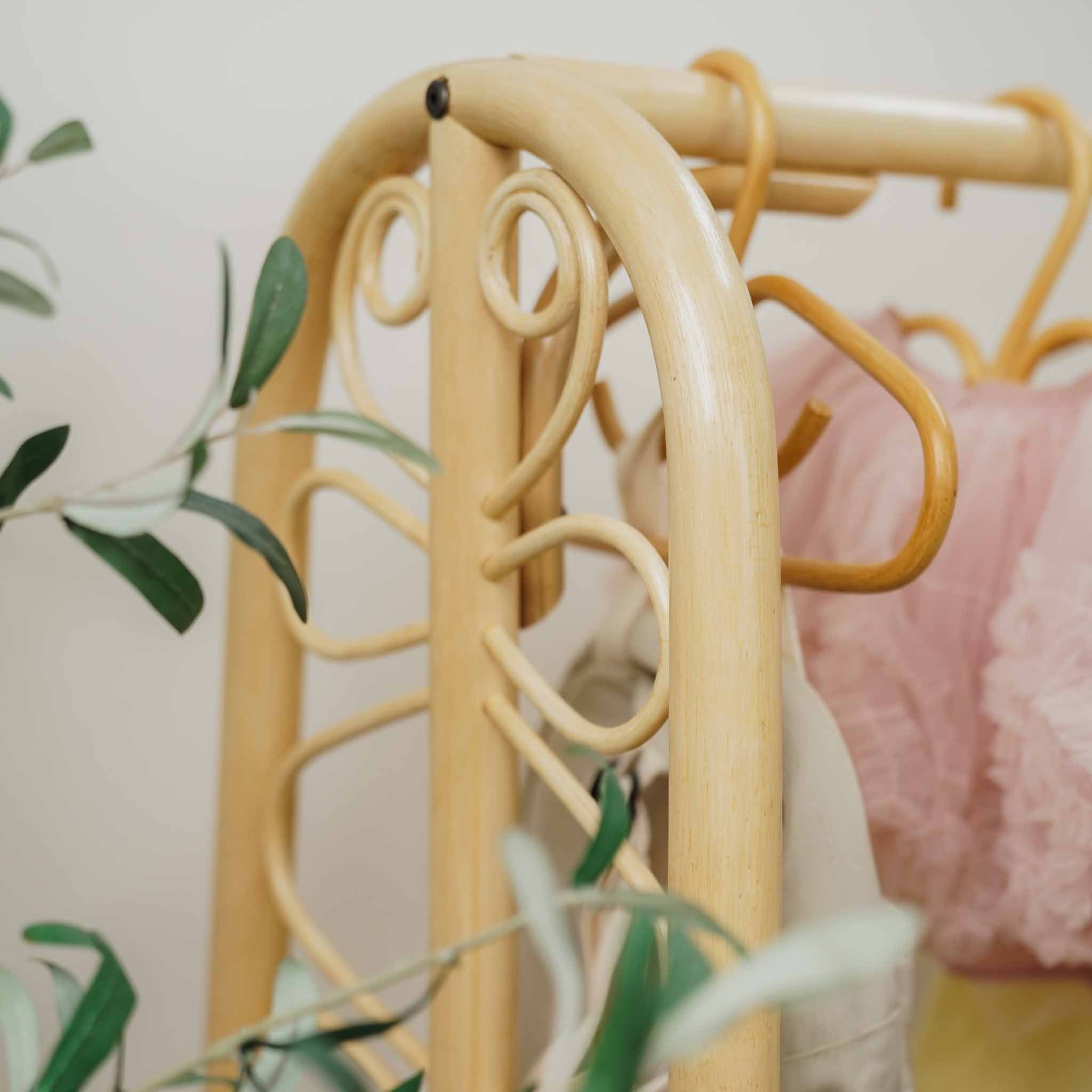 Close-up of the handcrafted natural rattan Belle Kids Montessori Clothing Rack by MOMIJI, highlighting its decorative curved scrollwork, sturdy hanging rail, and easy-to-assemble construction.