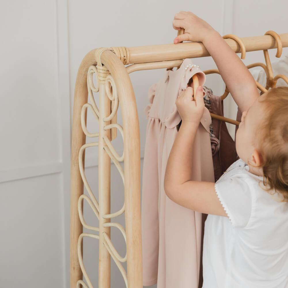 Close-up of a child hanging clothes on the Belle Kids Montessori Clothing Rack by MOMIJI.
