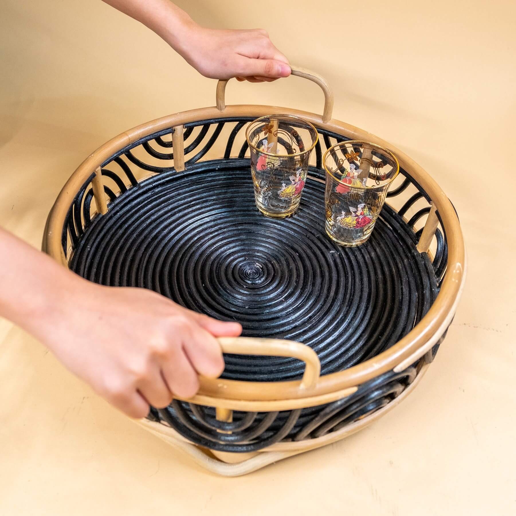Top view of a woman holding the Belle Tray by MOMIJI filled with drinking glasses.