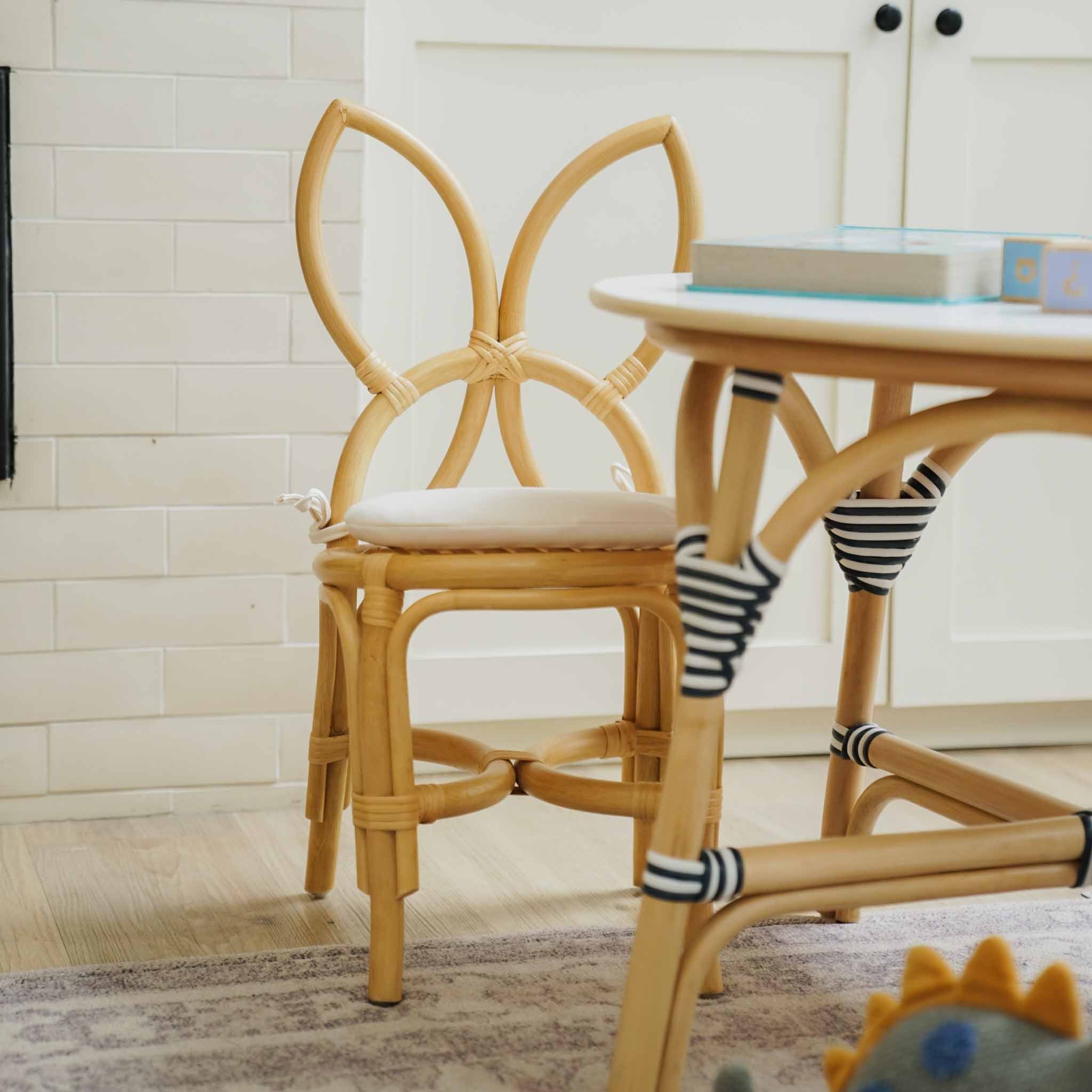 Handcrafted natural rattan wicker Butterfly Kids Chair by MOMIJI featuring a butterfly-wing backrest and removable cushion, styled with a round table in a playful room.
