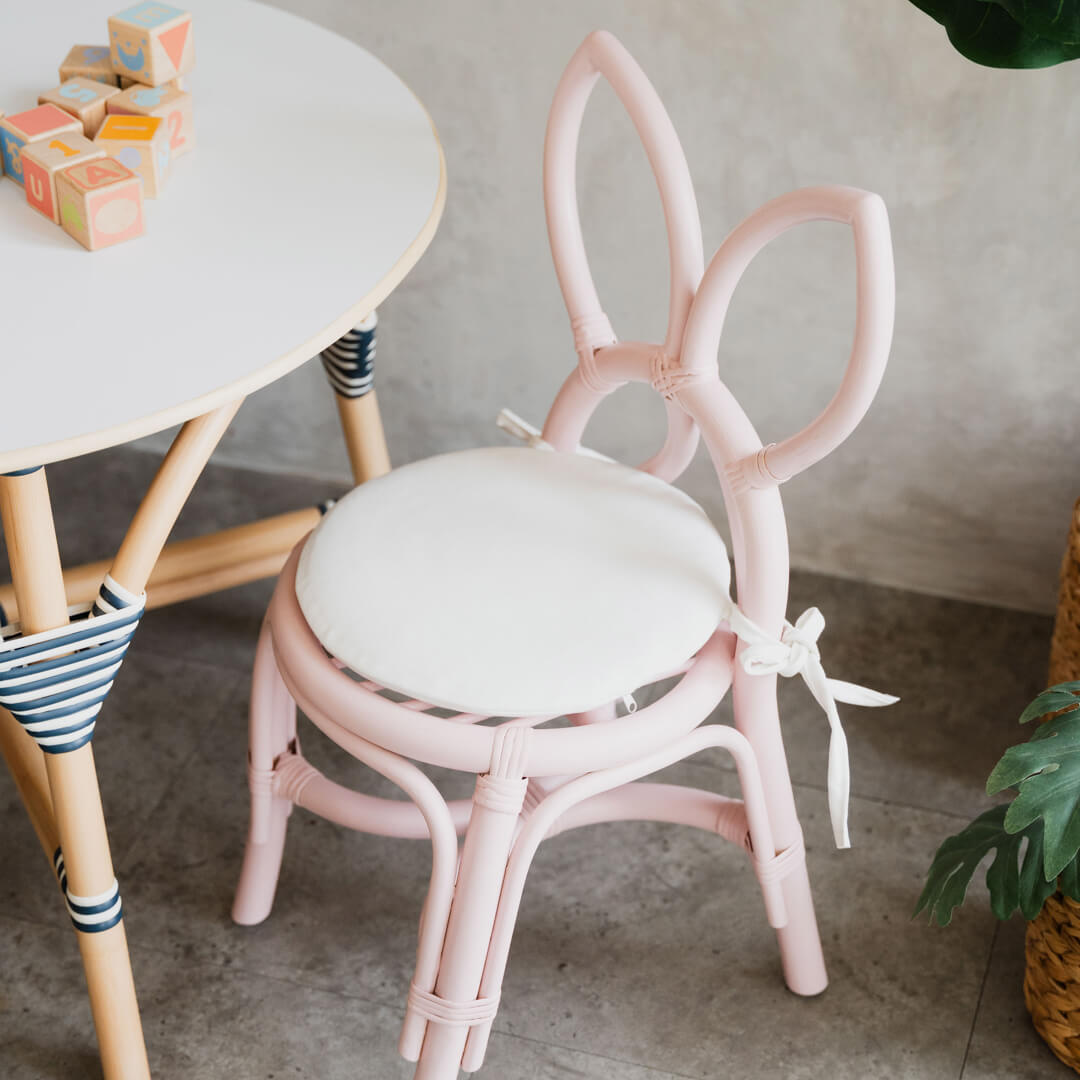 Pink butterfly kids chair by MOMIJI with a white cushion and colorful block on table.