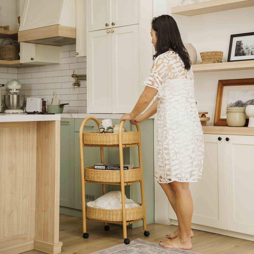 Woman pushing a handcrafted wicker rattan Con Craft Trolley by MOMIJI with smooth gliding wheels in a kitchen space