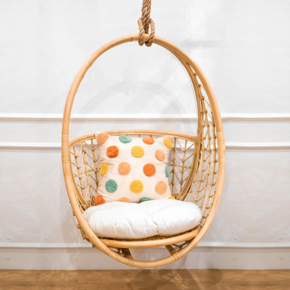 Front view of the Cross Hatch Hanging Chair by MOMIJI styled indoors with a white cushion and polka dot pillow.