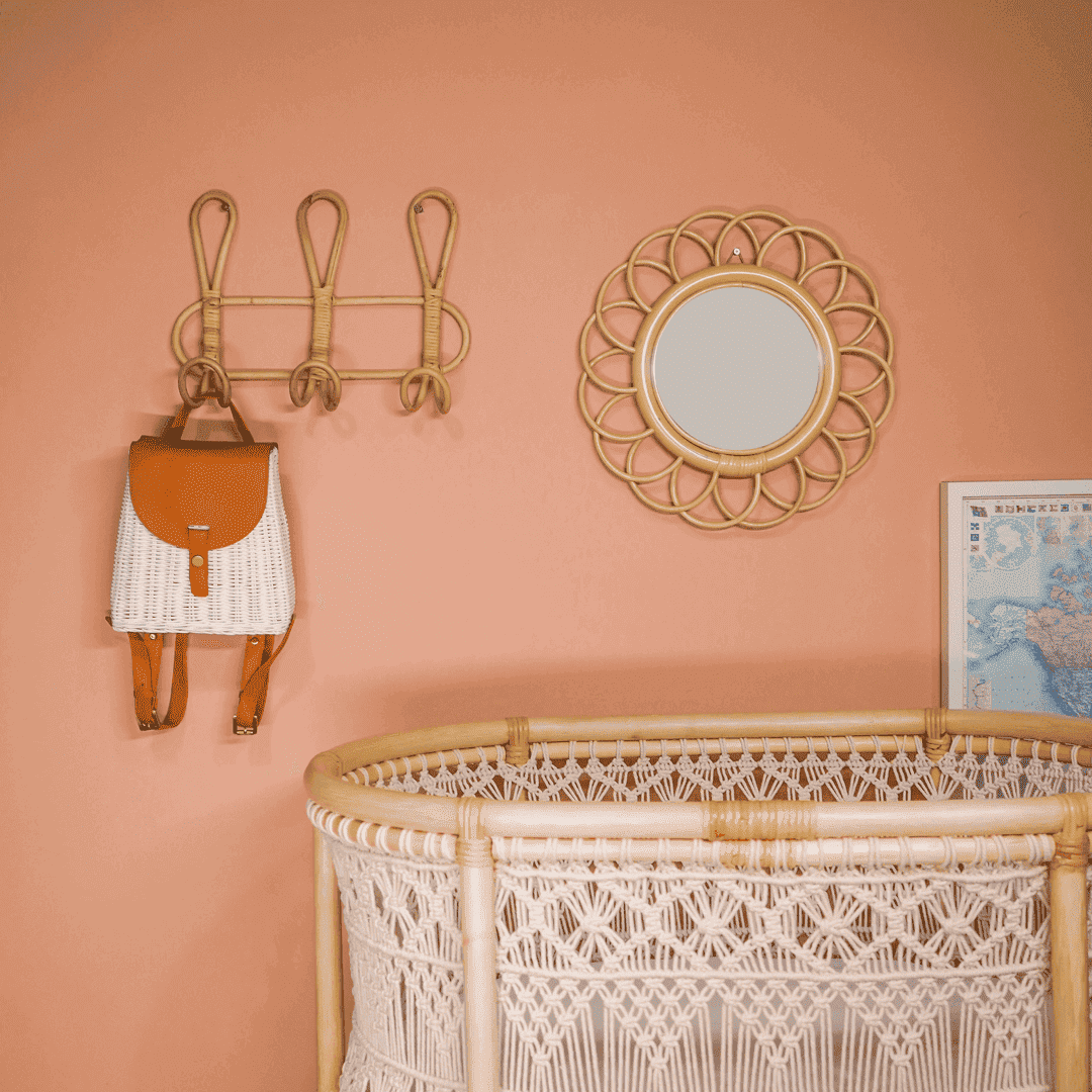 Dahlia Round Mirror – Small by MOMIJI mounted on the wall beside hooks in a room with a baby nest.
