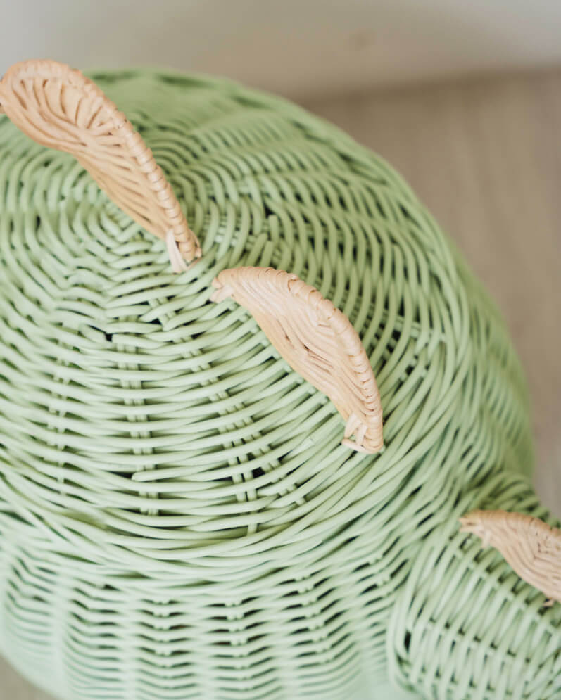 Close up shot of mint green dinosaur rattan storage basket's spine spikes.