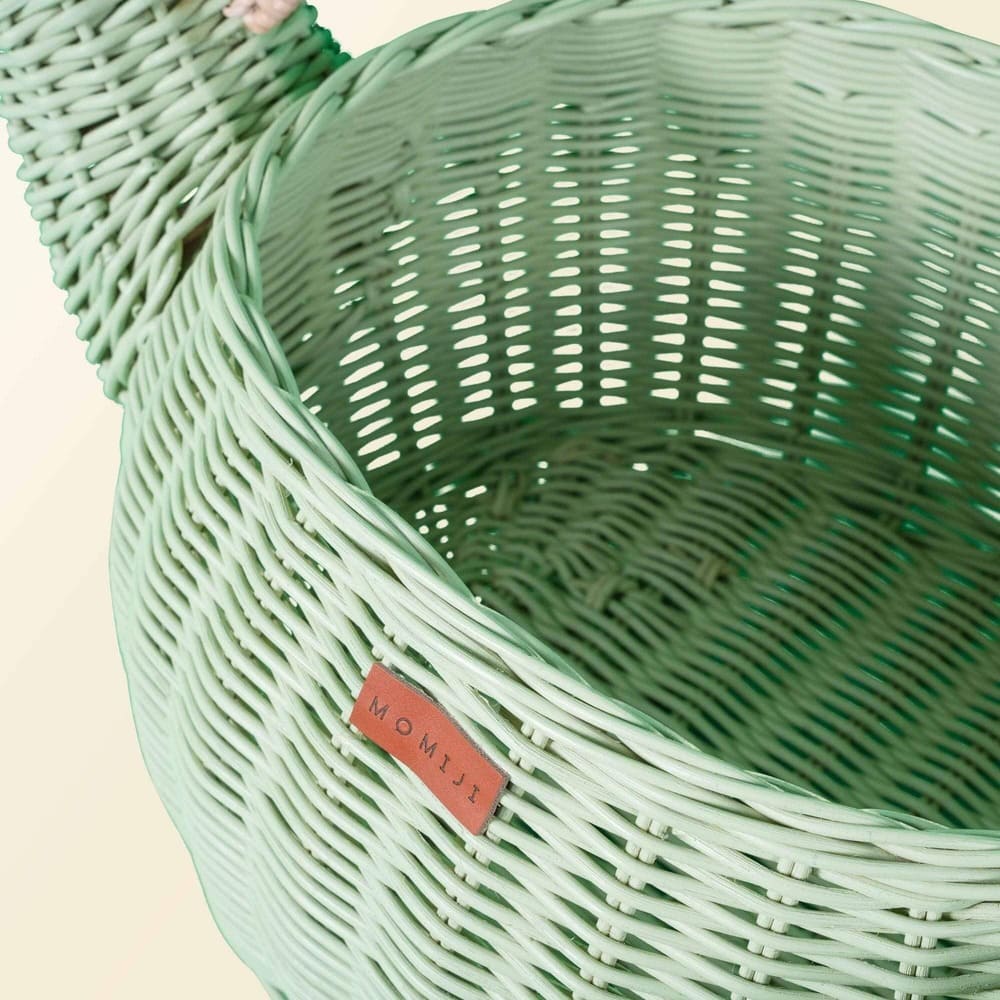Close up shot of MOMIJI logo on the mint green dinosaur rattan storage basket.