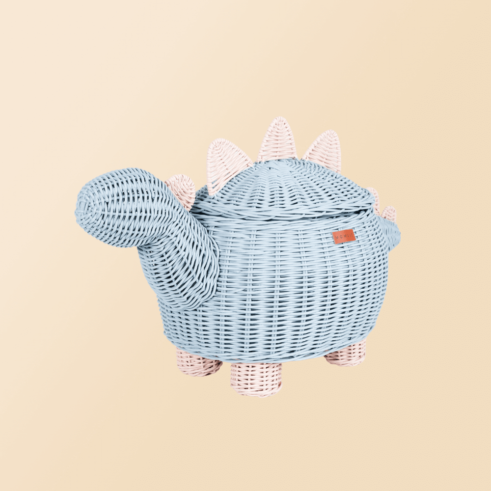 Tilted side view of pastel blue and pink dinosaur rattan storage basket by MOMIJI.