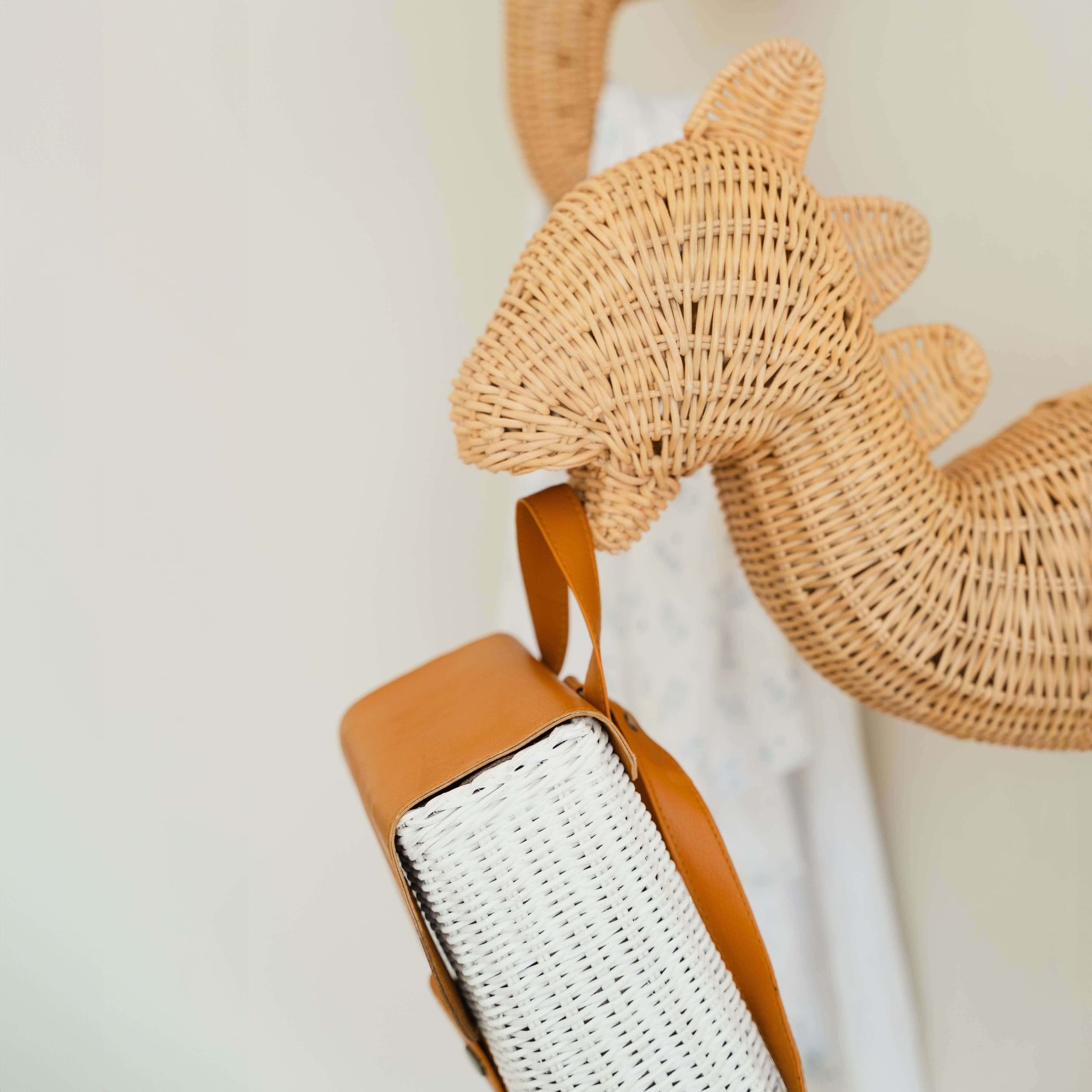 Side view of the Dinosaur Wall Decor by MOMIJI hanging a rattan bag on a decorative wall.