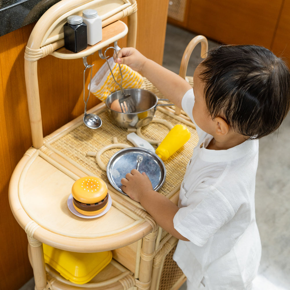Child hanging a spatula on the Dreamer Play Kitchen by MOMIJI.