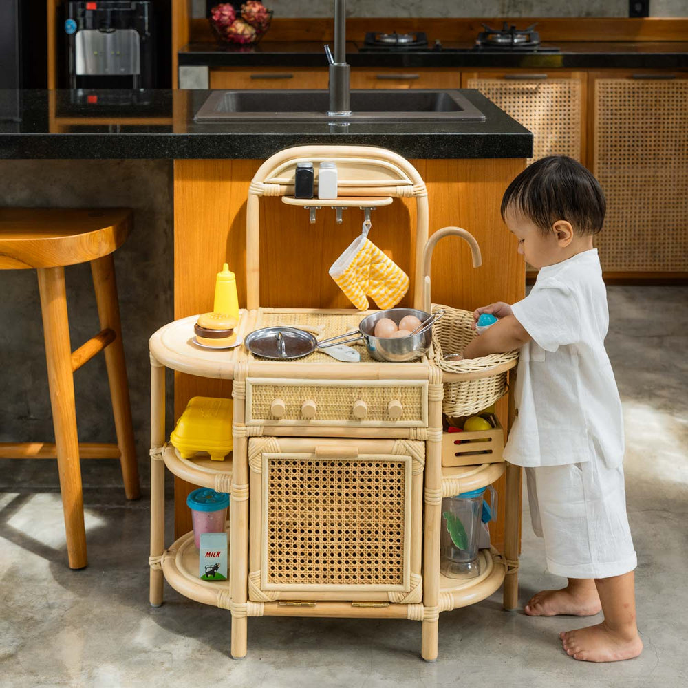 Child playing with the Dreamer Play Kitchen by MOMIJI in a kitchen setting.