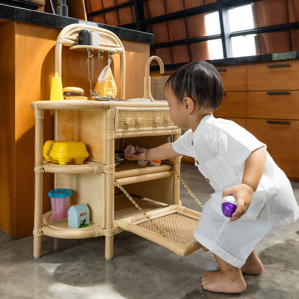 Child taking toys from inside the Dreamer Play Kitchen by MOMIJI.