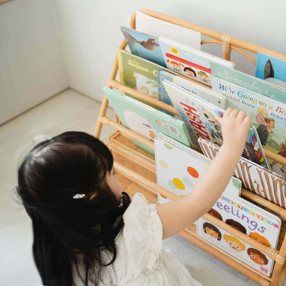 Child reaching for a book in Elena Kids Montessori Bookshelf – Natural by MOMIJI with children's books.