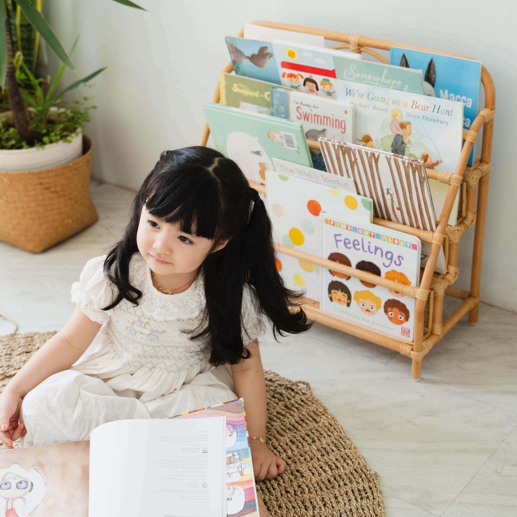 Child on the rug with a Elena Kids Montessori Bookshelf – Natural by MOMIJI in the background.