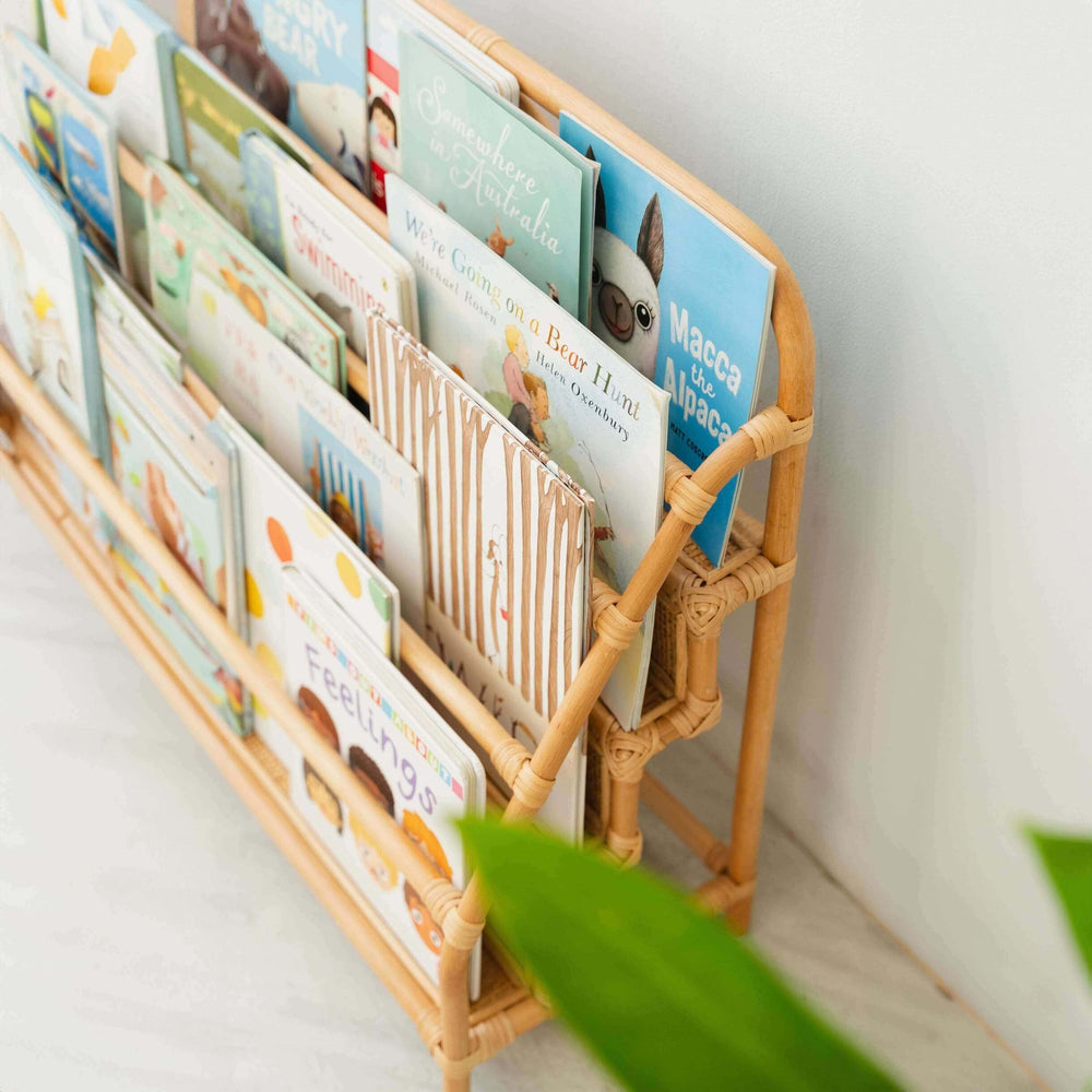Children's books are stored in the Elena Kids Montessori Bookshelf – Natural by MOMIJI in a room with indoor plants.
