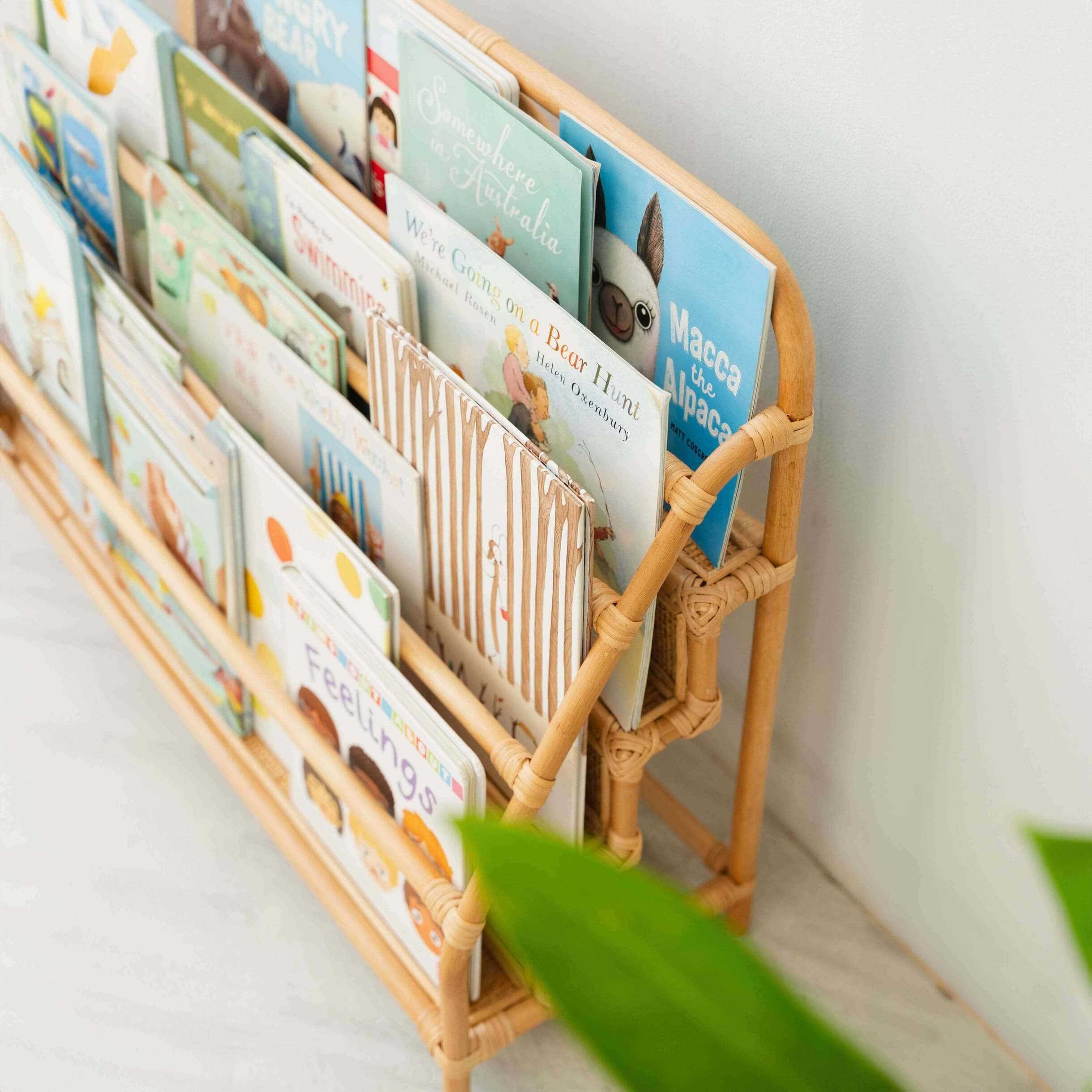 Children's books are stored in the Elena Kids Montessori Bookshelf – Natural by MOMIJI in a room with indoor plants.