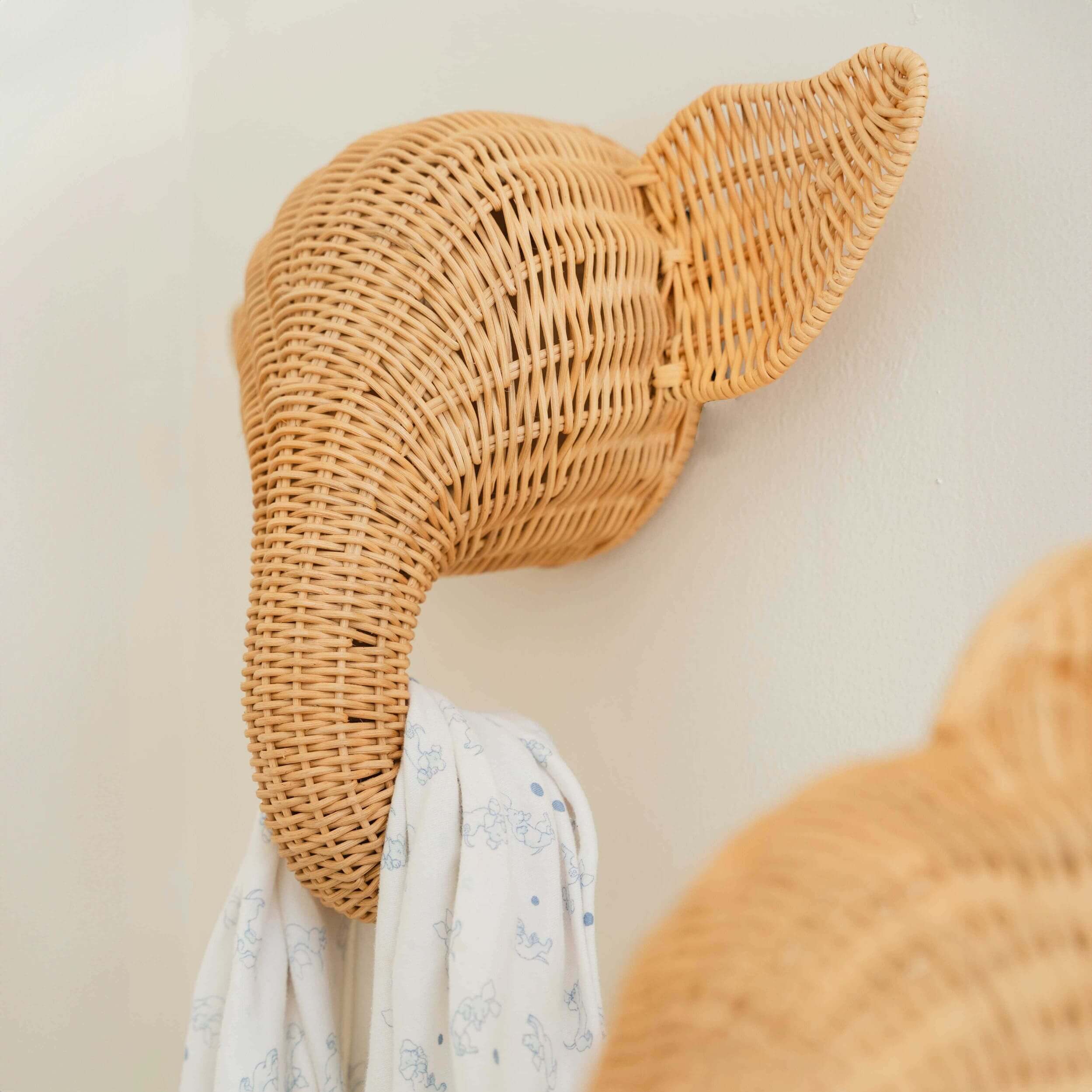 Close-up of the elephant wall decor by MOMIJI mounted on the wall and used to hang a white shirt.