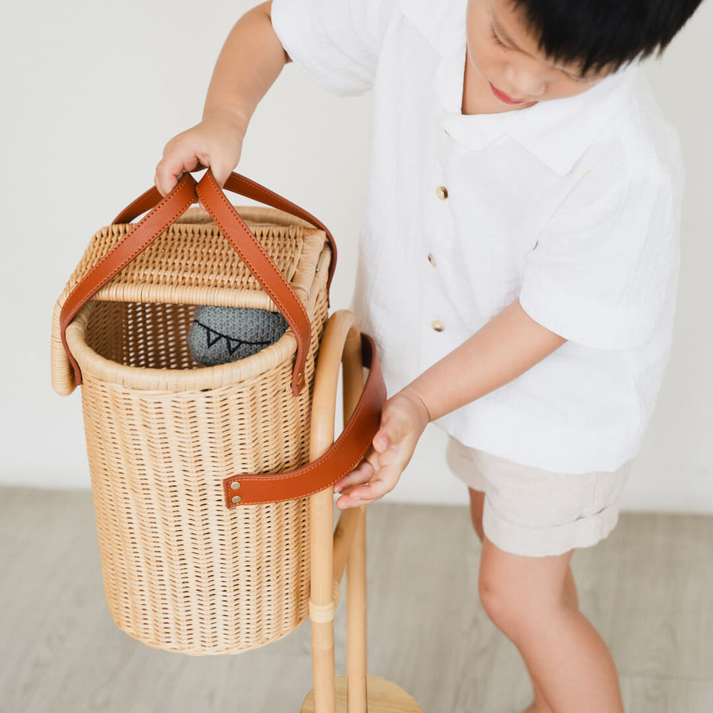 Child attaching the Eric Kids Shopping Trolley by MOMIJI in a cozy indoor space.