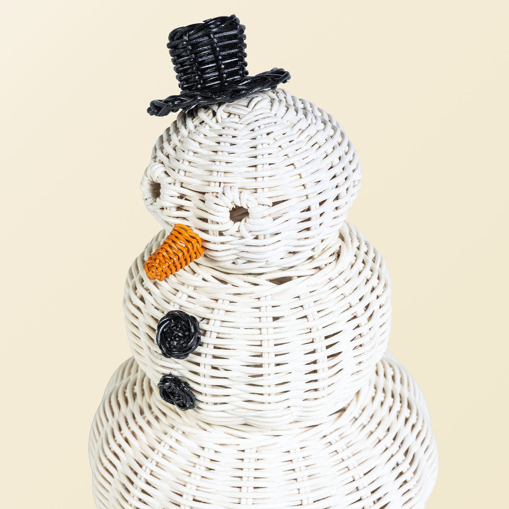 Close-up of a handcrafted rattan wicker snowman basket by MOMIJI showing the round eyes, black top hat, and black round button details.