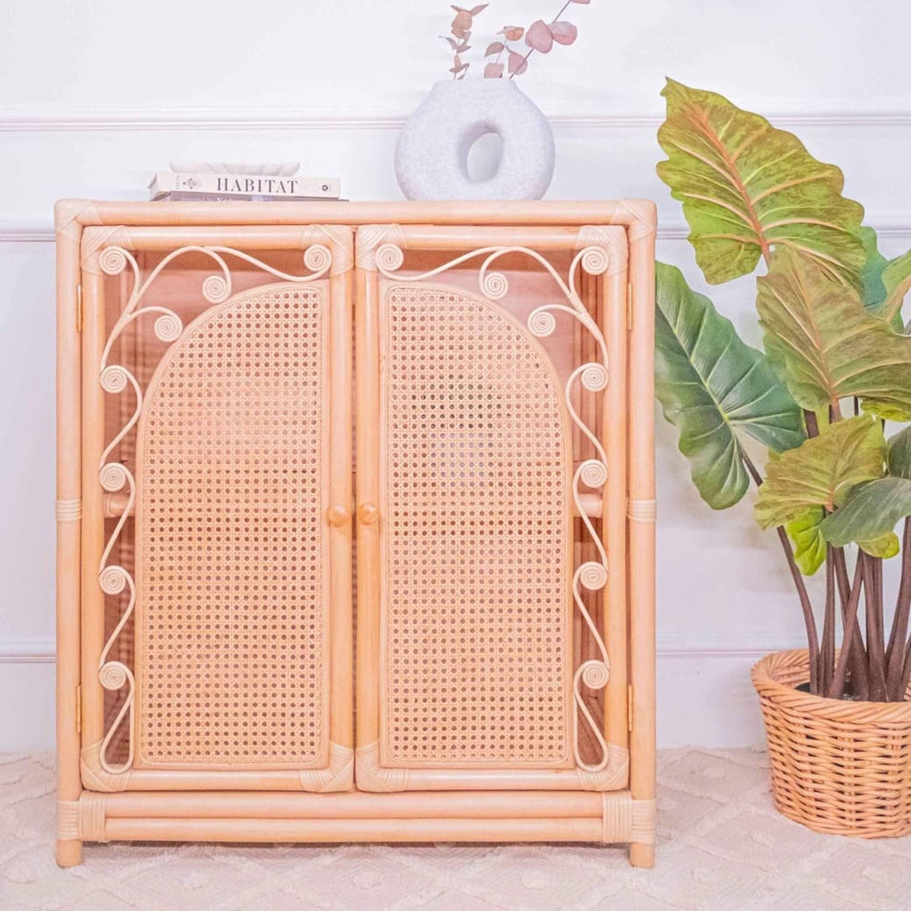 Front view of the handcrafted rattan Fern Storage Cabinet by MOMIJI styled with books and a vase on top.
