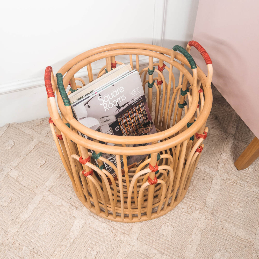 Top view of stacked handcrafted rattan wicker Floret baskets by MOMIJI filled with books on a rug.