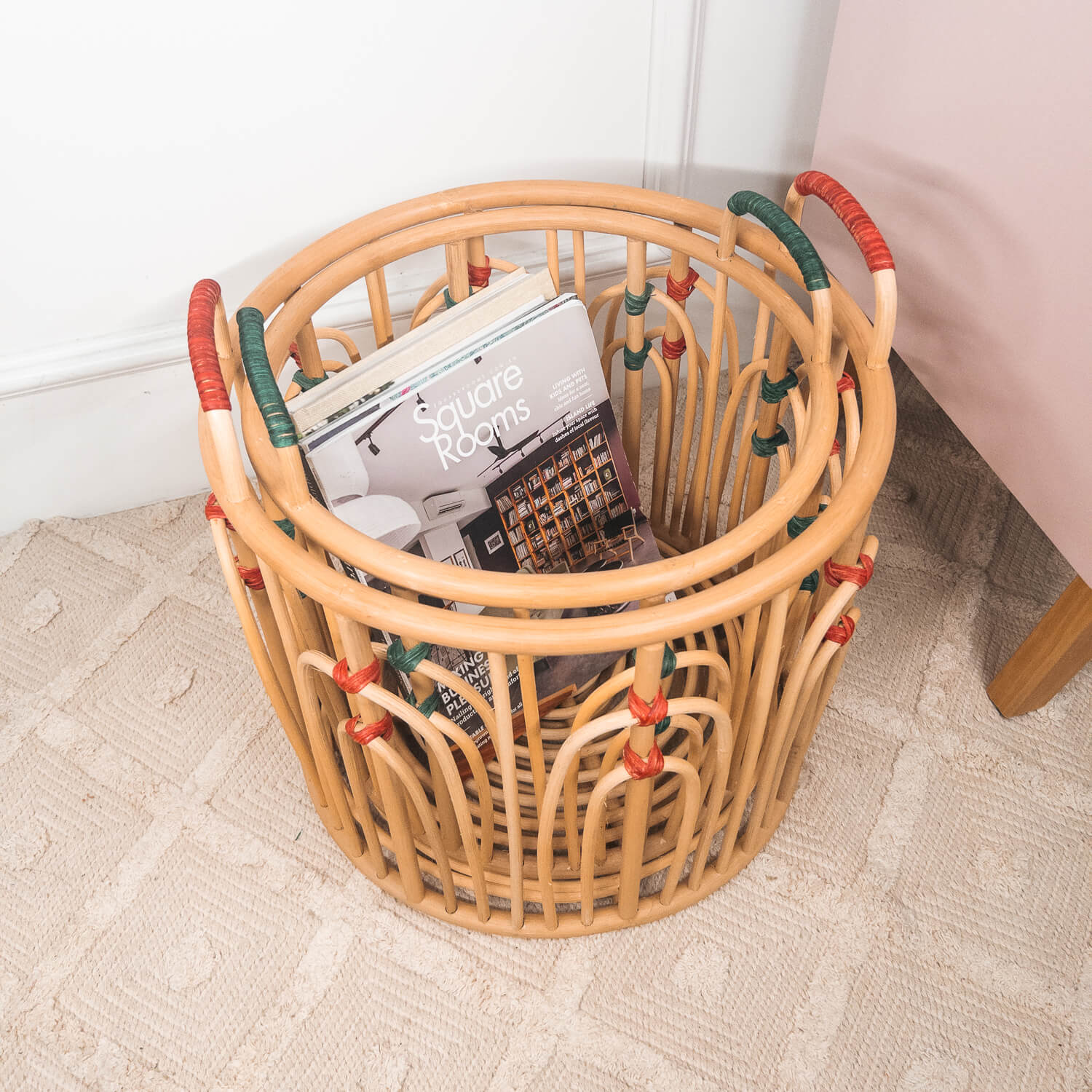 Top view of stacked handcrafted rattan wicker Floret baskets by MOMIJI filled with books on a rug.