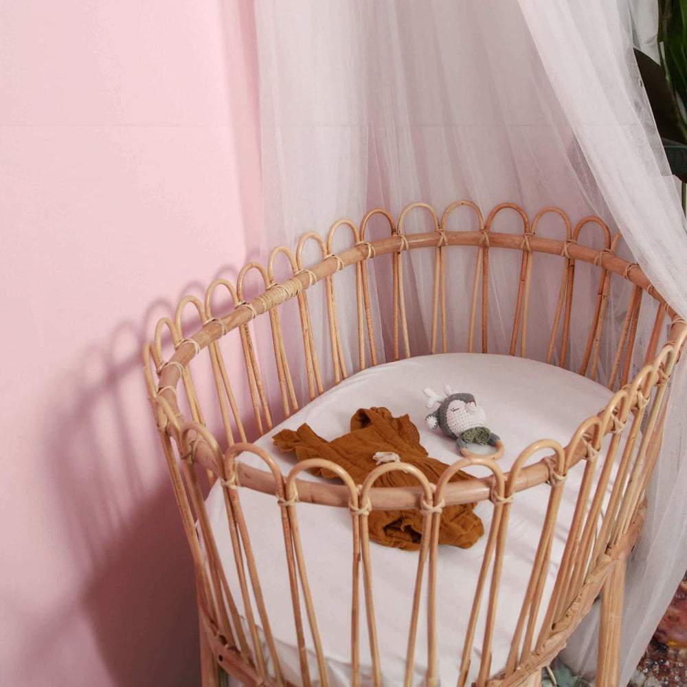 Inside view of the Gerhana Bassinet by MOMIJI with children’s clothes and toys.