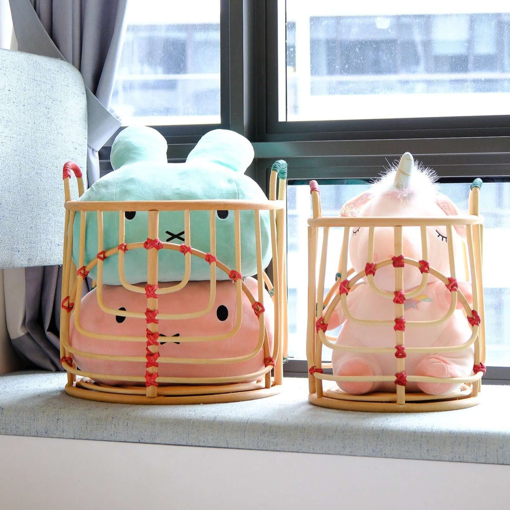 Handcrafted Iris baskets set by MOMIJI in natural rattan with red and green bindings, filled with pulsh toy with windows in background.