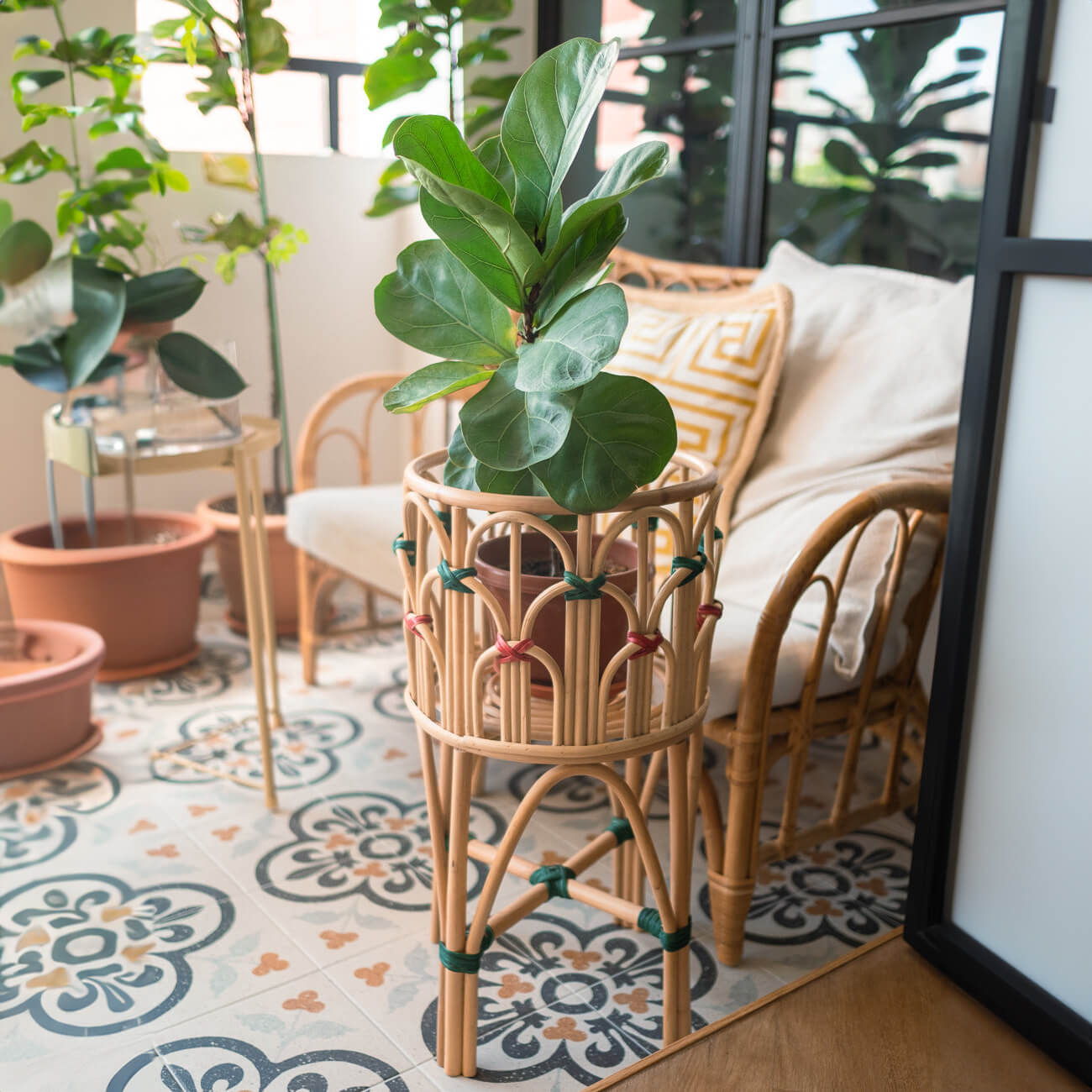 Iris Planter by MOMIJI holding a potted plant outdoors with a rattan chair in the background.