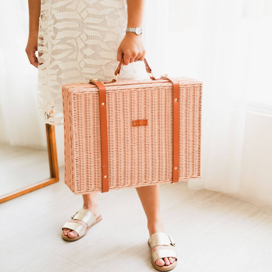 Woman holding the Jasmine rattan Suitcase by MOMIJI in a room with a mirror.