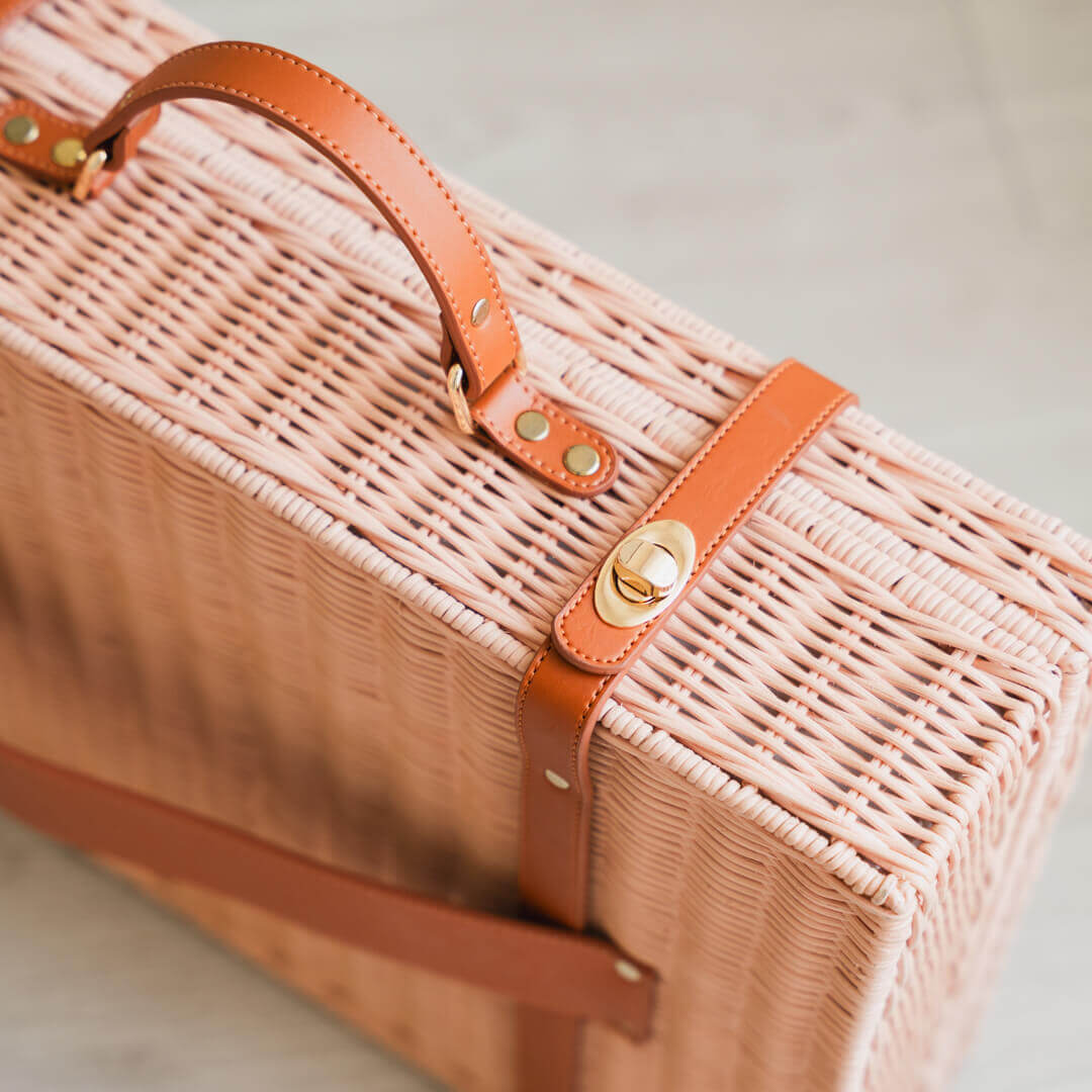 Close-up of the lock detail of the Jasmine rattan Suitcase by MOMIJI placed on the floor.