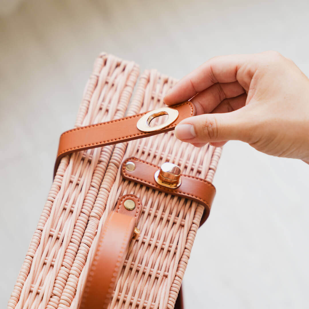 Close-up of a woman’s hand opening the lock of the Jasmine rattan Suitcase by MOMIJI.
