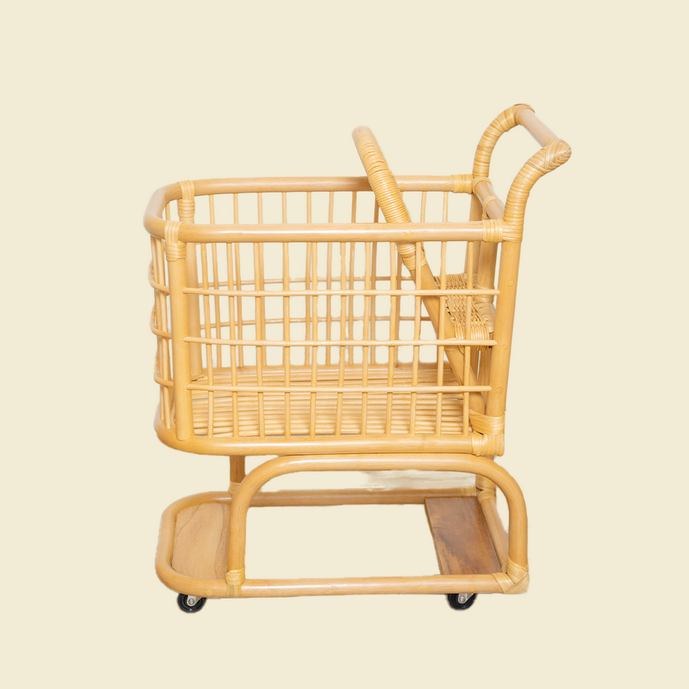 Side view of the handcrafted wicker rattan Kids Shopping Cart by MOMIJI, highlighting its sturdy frame, smooth rolling wheels, and spacious basket with doll seat