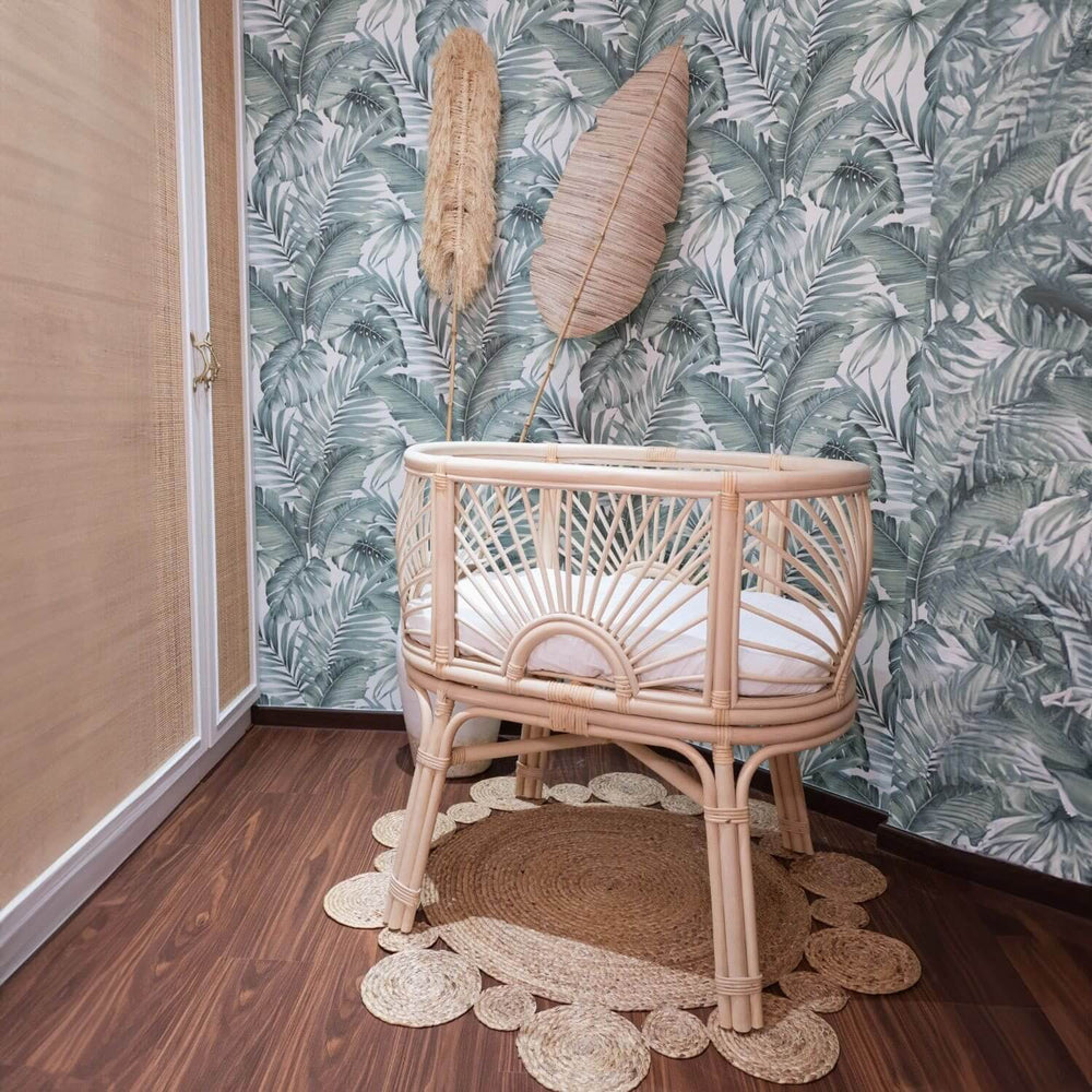Side view of the Kraton Bassinet by MOMIJI placed on a rug with a white mattress in a decorated room.