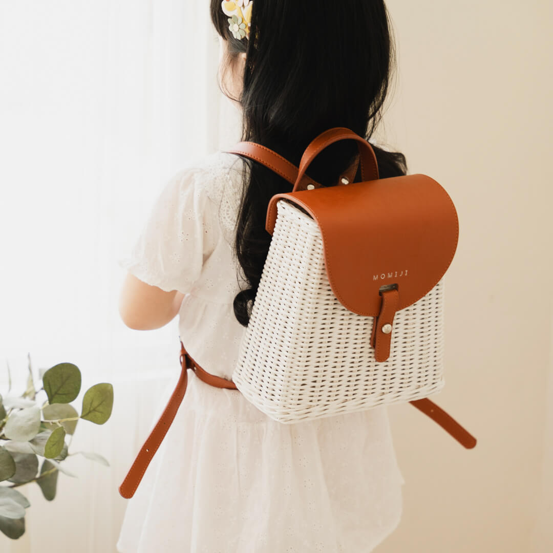 Child wearing the handcrafted rattan Layla Backpack by MOMIJI, designed for kids and adults with adjustable leather straps.
