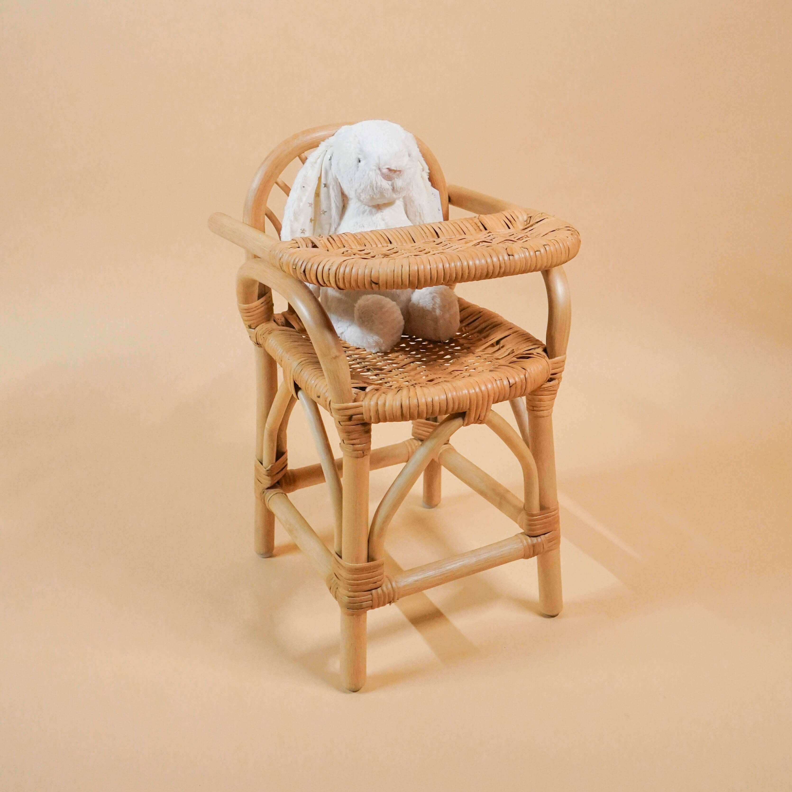 Angled view of the handcrafted rattan wicker Layla Doll High Chair by MOMIJI with a bunny doll seated.