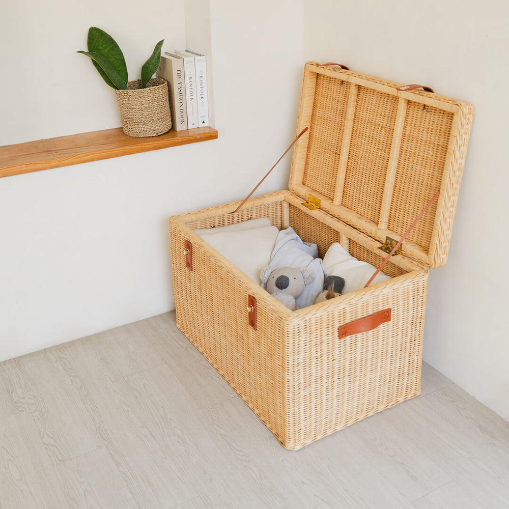 Handcrafted rattan wicker Leon Leather Trunk by MOMIJI opened to reveal kids toys inside, with side support straps to hold the lid open safely.