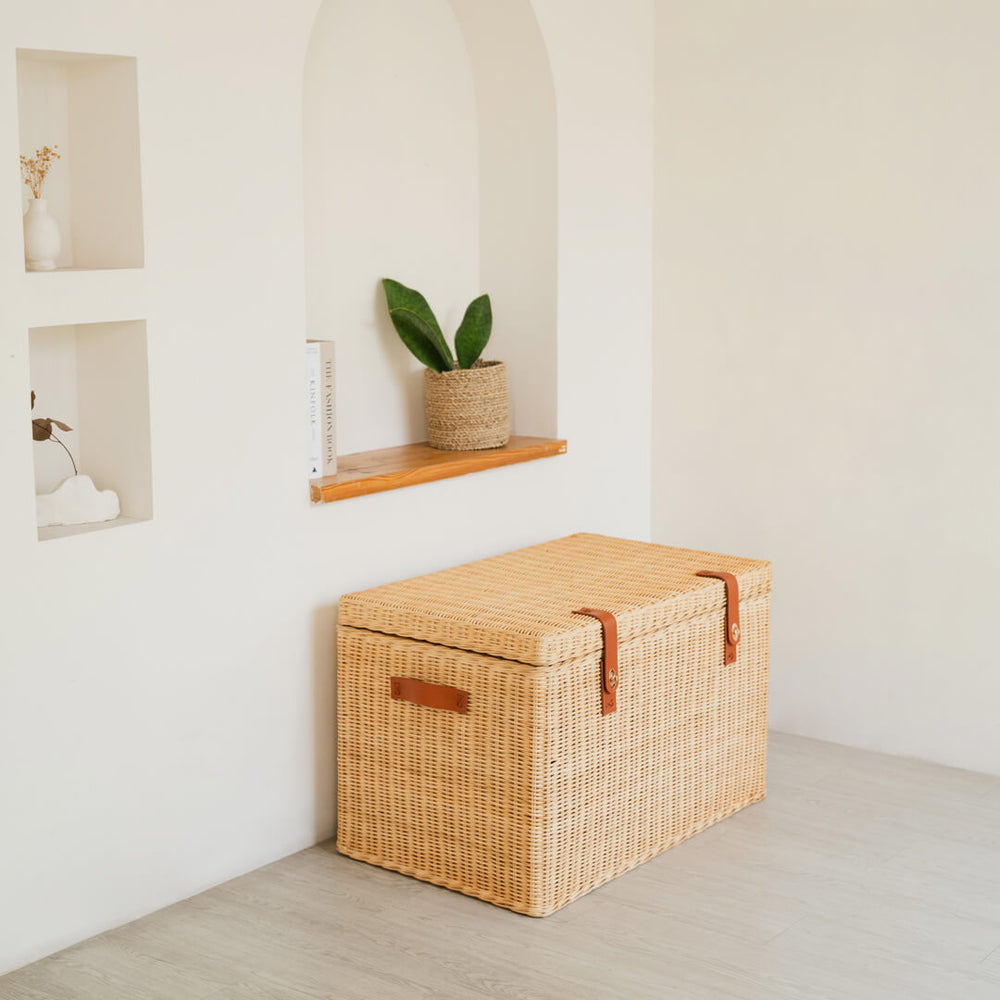 Side view of the handcrafted rattan wicker Leon Leather Trunk by MOMIJI, showing leather side handle and front lock for easy lifting.