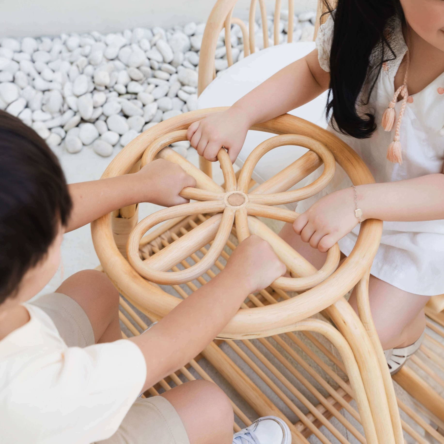 Close-up of a child’s hand holding the carved floral handle detail on the Leon Rocking Bench by MOMIJI.