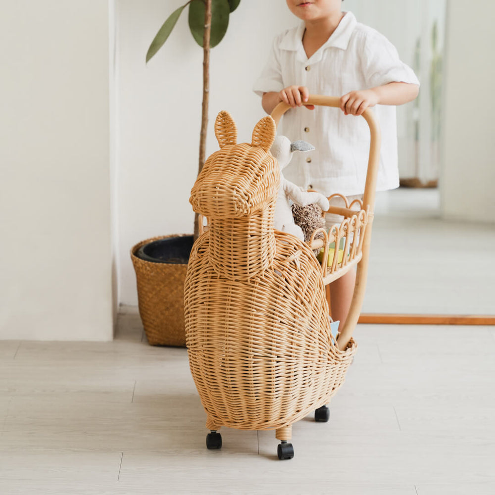 Close-up of the front section of the Llama Craft Trolley by MOMIJI filled with children’s toys, with indoor plants in the background.