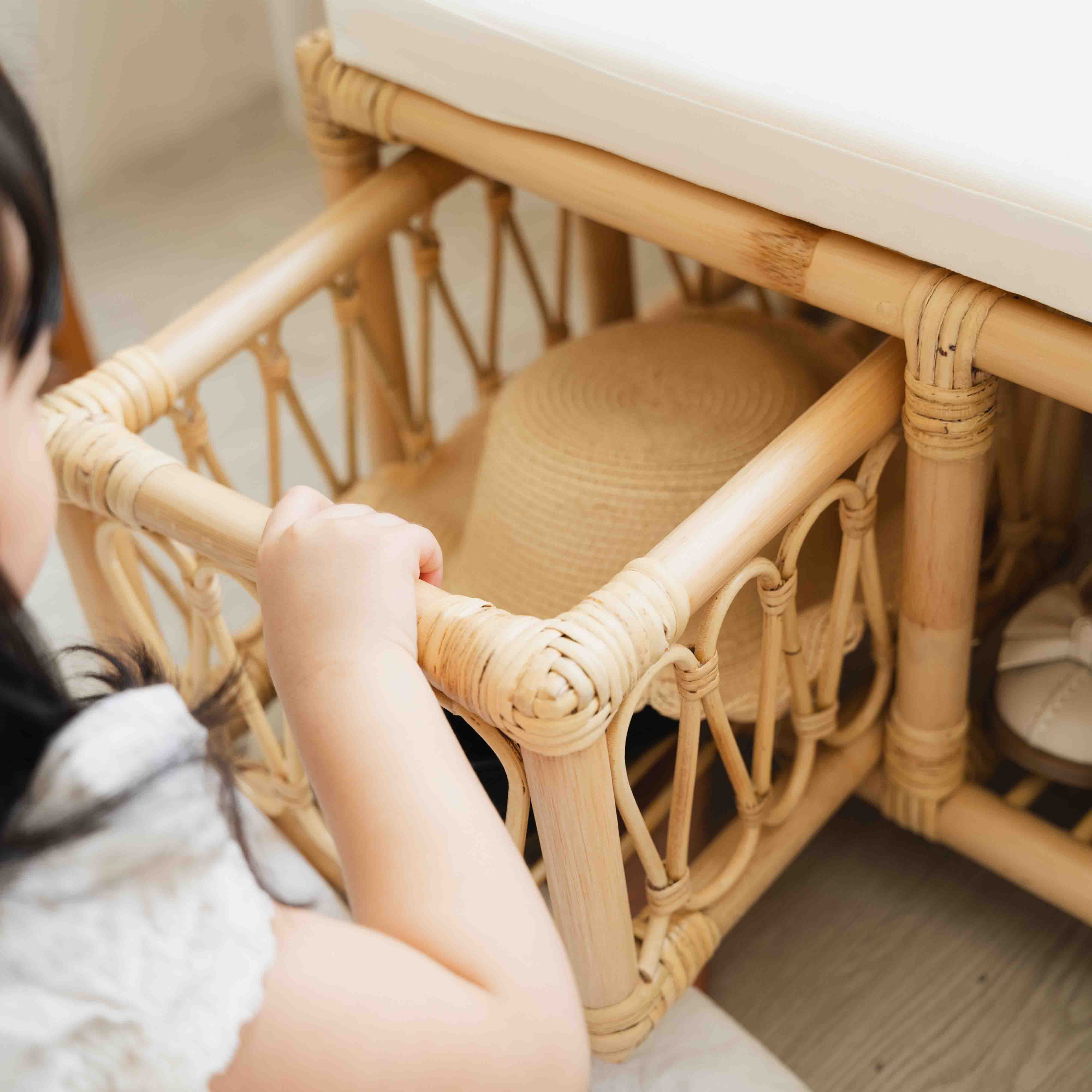 Child pulling out a lower storage drawer of the Luke Kids Bench by MOMIJI containing hats.