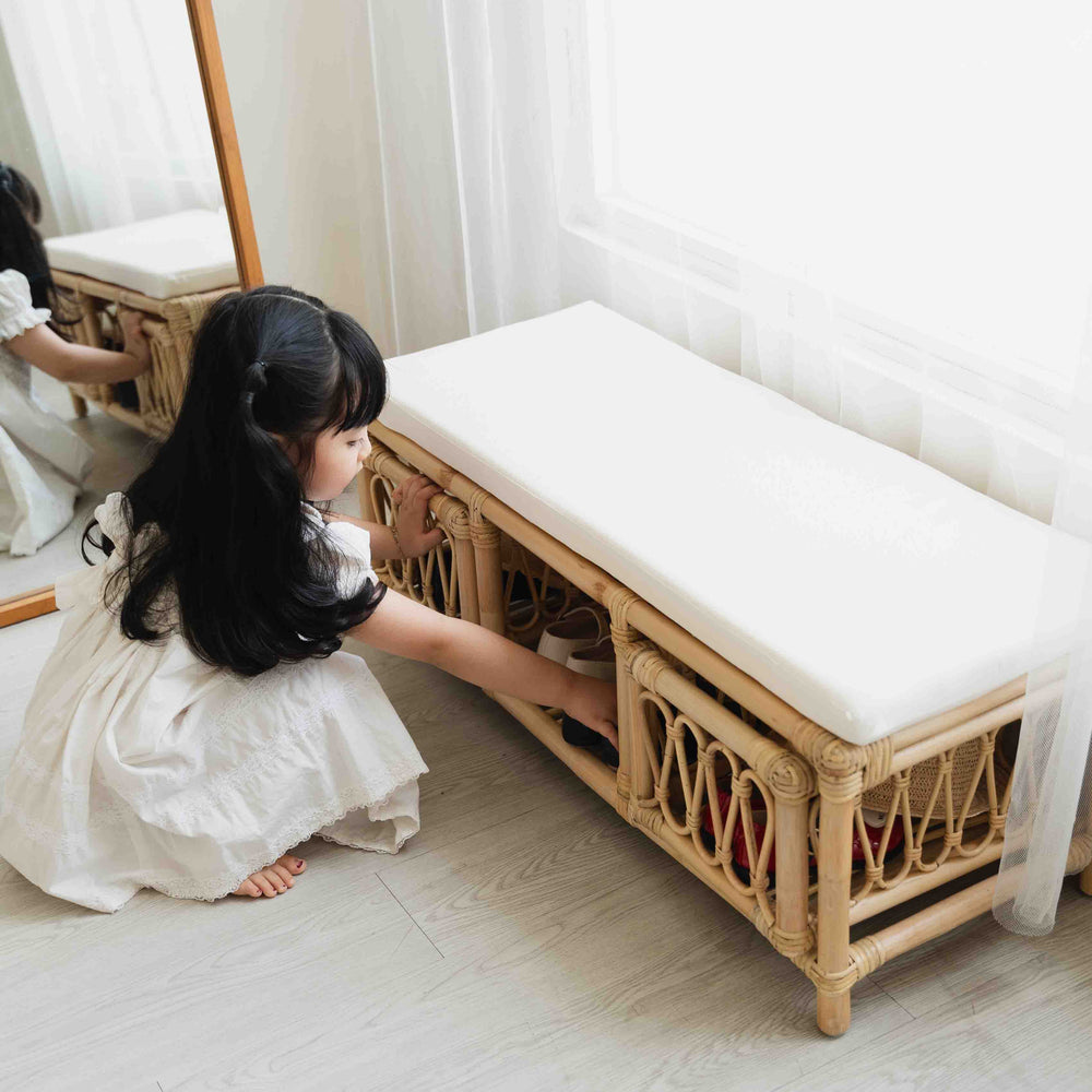 Child storing shoes in the lower storage compartment of the Luke Kids Bench by MOMIJI.