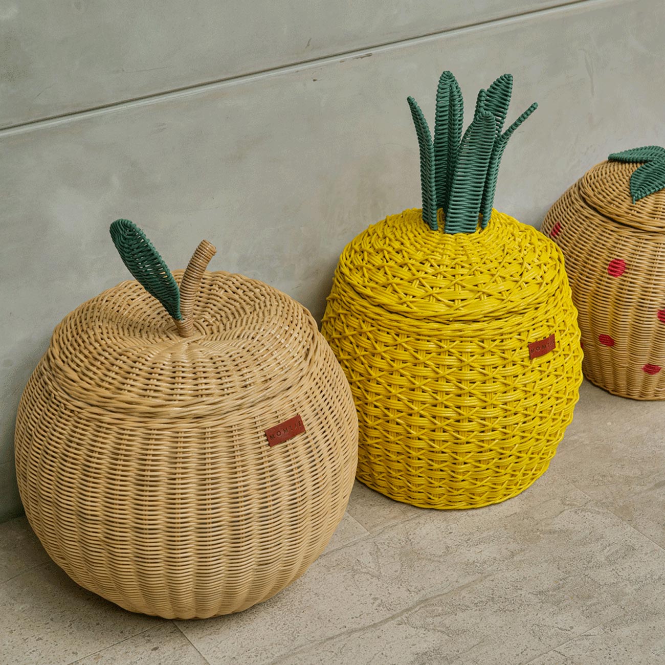 Natural Apple Rattan Storage Basket next to Yellow Pineapple Rattan Storage basket and Strawberry Rattan Storage Basket in medium sizes by MOMIJI.