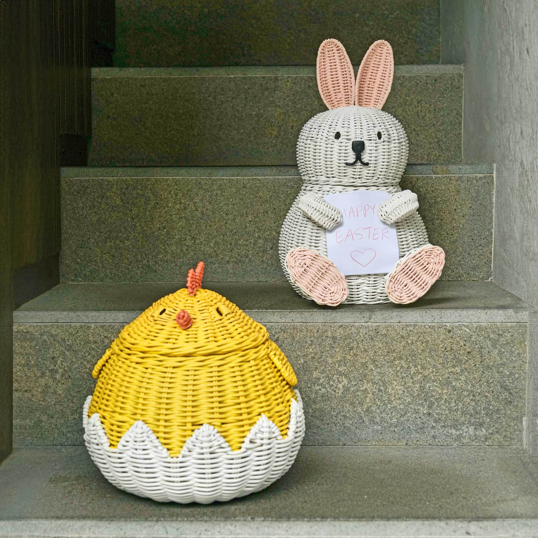 Bunny and Chick Rattan Storage Basket by MOMIJI on stone steps.