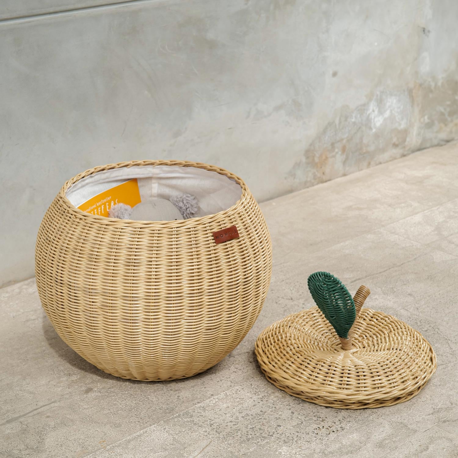 Natural apple rattan storage basket by MOMIJI, opened lid with toys and books inside.