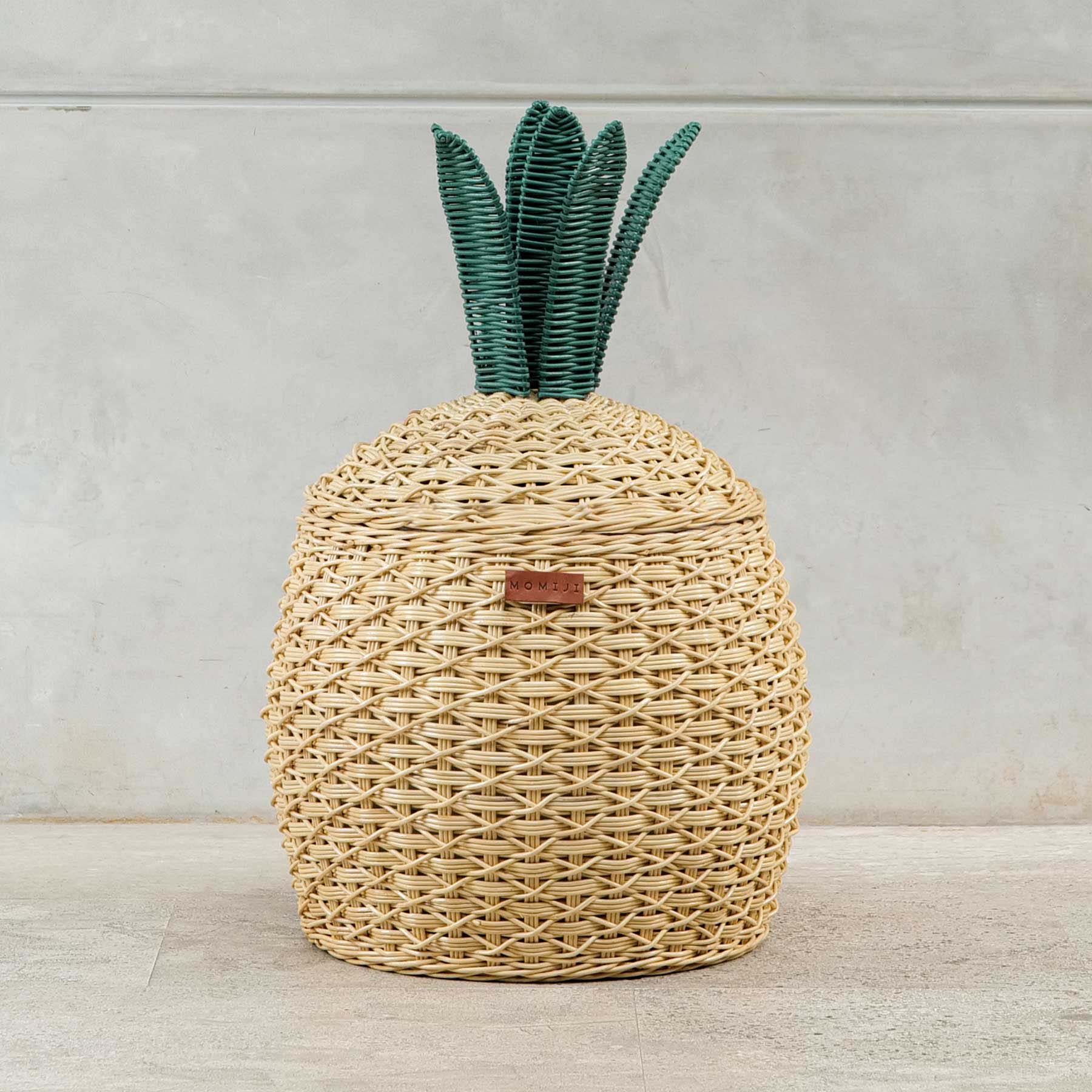 Front view shot of Pineapple Rattan Storage Basket by MOMIJI on a light wooden floor.