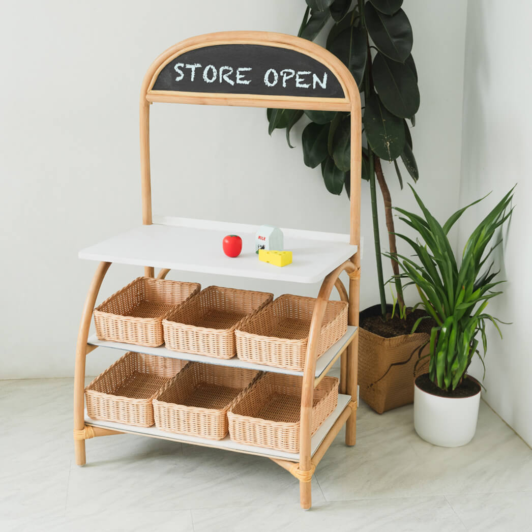Angled front view of the 3-in-1 play furniture by MOMIJI in grocery store mode, styled with a rattan basket in a room with indoor plants.